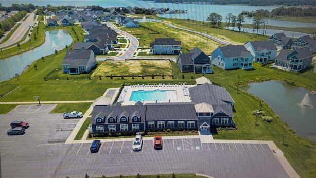 An aerial view of a residential area with houses, a swimming pool, and a parking lot.