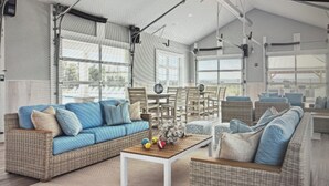 A spacious indoor area with wicker furniture, including sofas and chairs, arranged around a central table.
