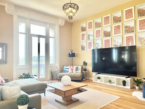 A living room with a large TV, a fireplace, and a view of the city.