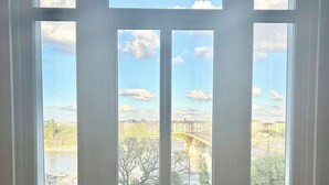 A view through a window with a clear sky and a bridge in the background.