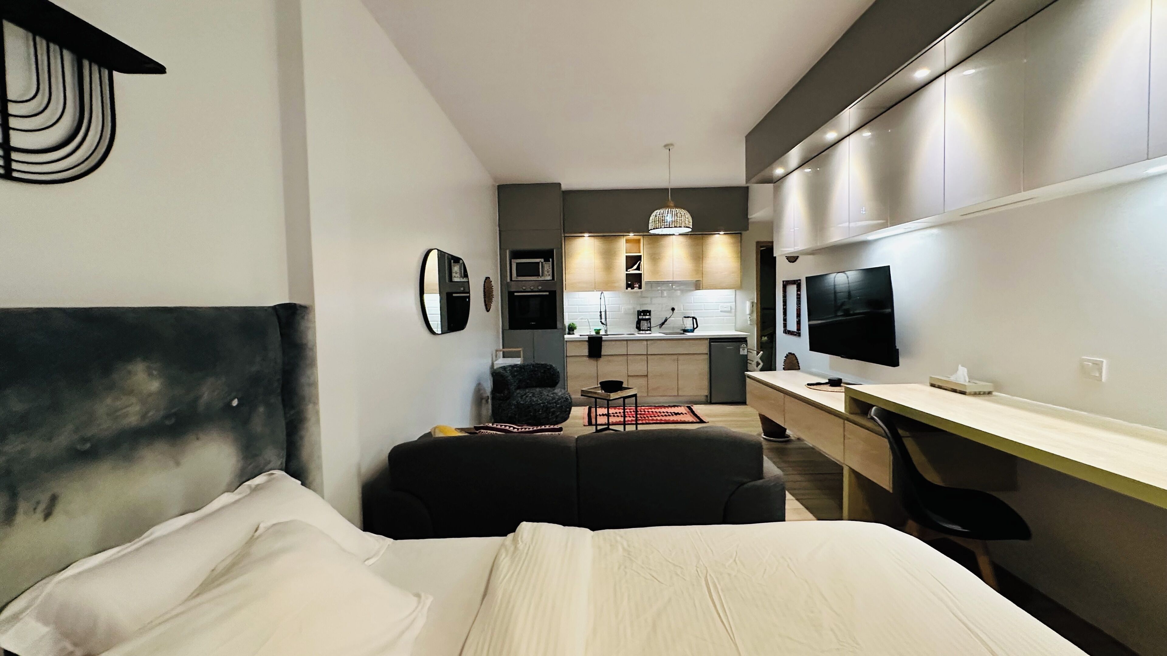 Une chambre d’hôtel moderne équipée d’un lit, d’un bureau, d’une chaise, d’une télévision et d’une kitchenette.