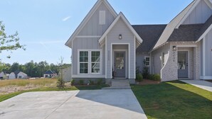 A two-story house with a front porch, a driveway, and a well-maintained lawn. - Charming 2-bedroom townhome with WiFi and AC in Auburn (Auburn)