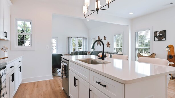 A modern kitchen with white cabinetry, a central island, and a dining area with a sofa. - Charming 2-bedroom townhome with WiFi and AC in Auburn (Auburn)