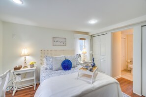 Una camera da letto con un letto, comodini, una lampada, un elemento decorativo a parete e vista sul bagno.