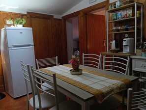 Une cuisine équipée d’un réfrigérateur, de meubles de rangement en bois, d’une machine à café et d’une étagère contenant des produits alimentaires.