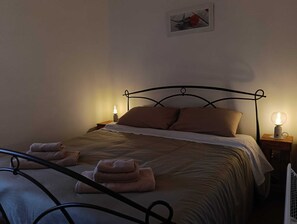 Un lit avec un cadre en métal, deux tables de chevet avec des lampes et un tableau au mur.