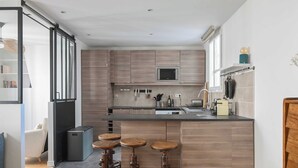 Une cuisine moderne dotée d’un îlot central, de tabourets de bar et d’une porte coulissante donnant sur une autre pièce.