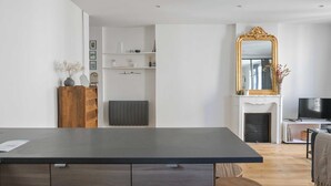 Une cuisine moderne avec un plan de travail foncé, des armoires en bois et un mur blanc agrémenté d’étagères.