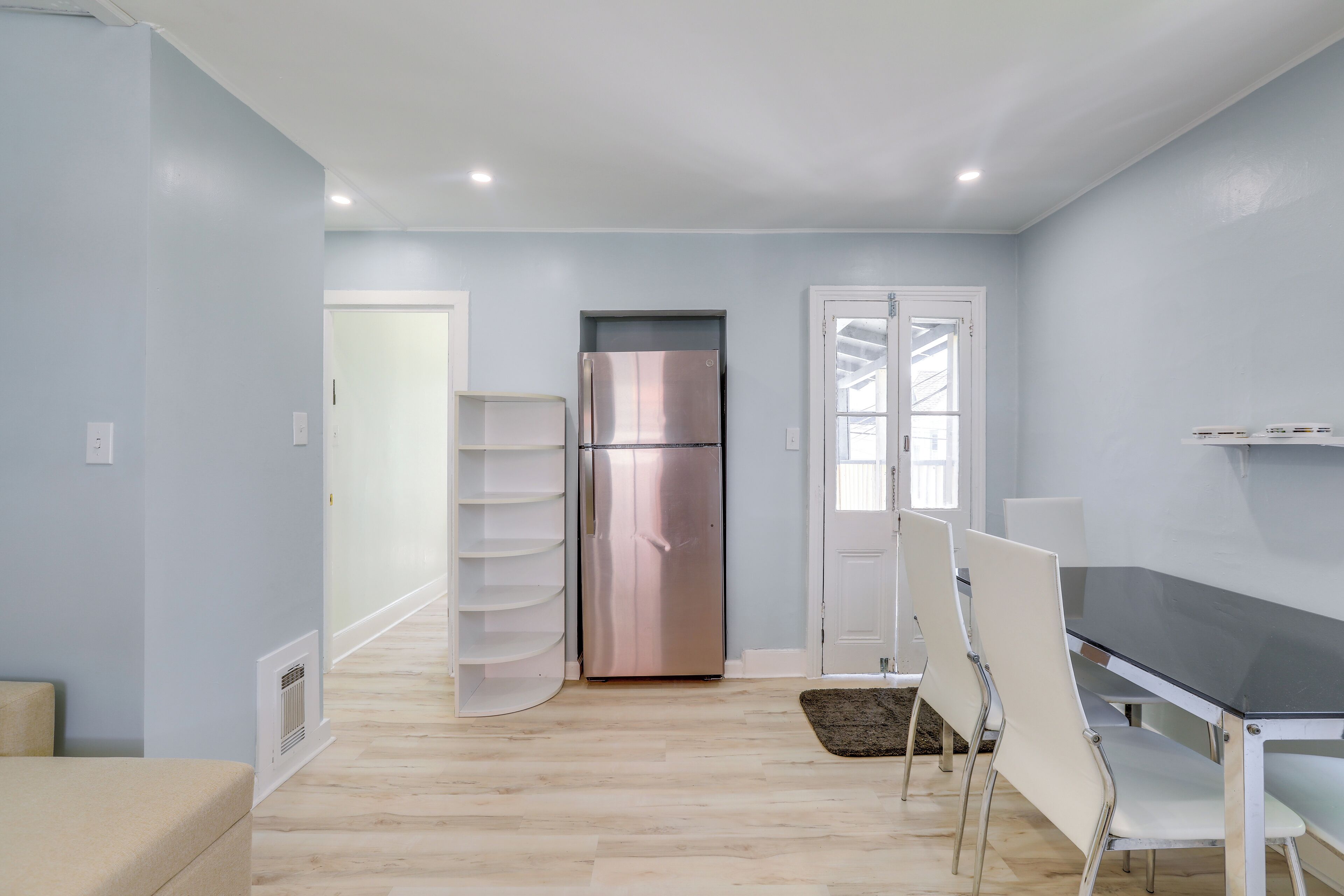 Une cuisine moderne avec un réfrigérateur en acier inoxydable, des chaises blanches et une table à manger noire.