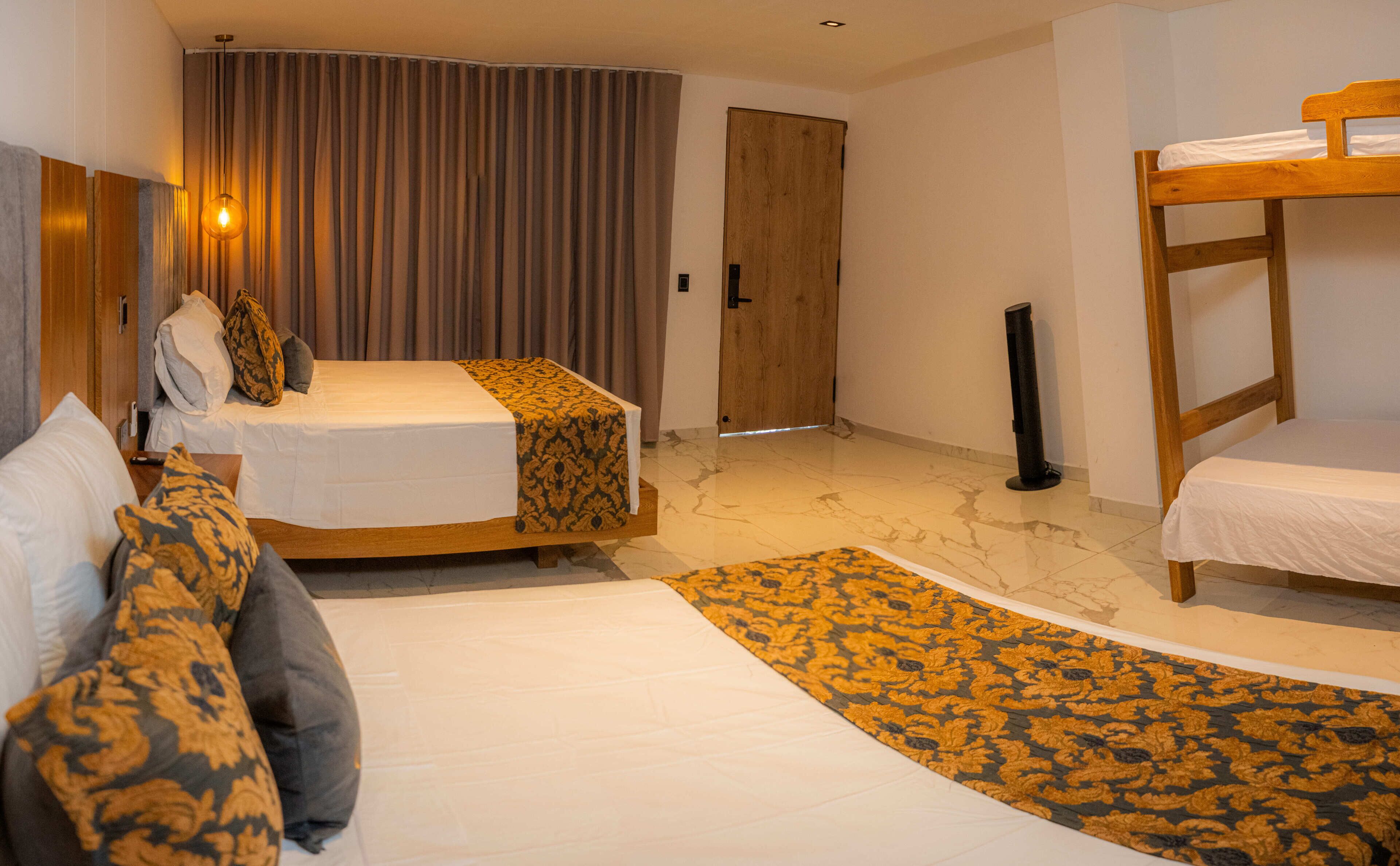 Camera d'albergo con due letti, un armadio in legno, un comodino con lampada e un tappeto decorato.