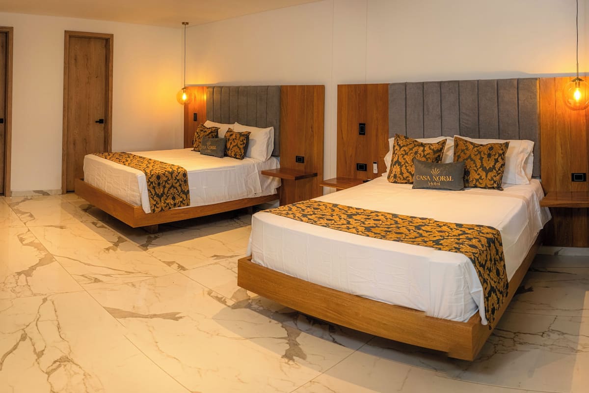 A hotel room with two beds, wooden headboards, marble flooring, and a wooden door.