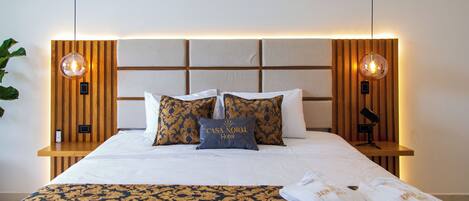 A neatly made bed with a patterned bedspread, a pillow with "CASA NORD Hotel" text, and two bedside lamps.