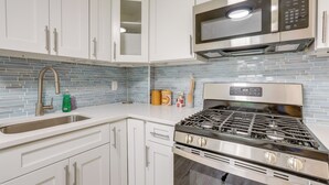 A modern kitchen with white cabinets, a stainless steel stove, and a microwave. - Walk to Beach & Dtwn: Apt in Ocean Grove (Ocean Grove)