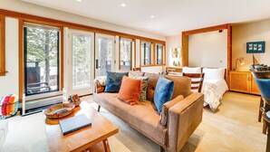 A spacious living area with a large sofa, a dining table, and a kitchen area visible through the glass doors. - Hike, Sled & Ski! Cozy Tahoe City Condo w/ Hot Tub (Tahoe City)