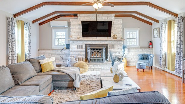 A spacious living room with a fireplace, a large TV, and a ceiling fan. - Poconos Group Getaway w/ Game Room + Fire Pit! (Covington Township)