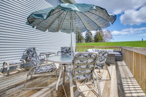 Une terrasse extérieure avec une table ronde, quatre chaises et un grand parasol.