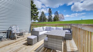 An outdoor deck with wicker furniture, a table, and a chair. - Algoma Lake Michigan Home w/ Game Room & Deck (Algoma)