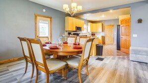 A dining area with a wooden table and chairs, a chandelier, and wooden cabinets. - Algoma Lake Michigan Home w/ Game Room & Deck (Algoma)