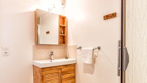 A bathroom with a wooden vanity, a mirror, a sink, and a towel rack.