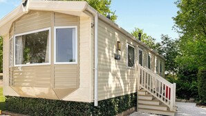 A single-story mobile home with a covered porch, a staircase, and a small garden area. - 3 bedroom accommodation in Ruthin and the Clwydian Range (Ruthin and the Clwydian Range)