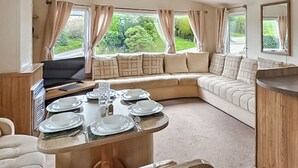 A cozy RV interior with a dining table set for four, a sofa, and a TV. - 3 bedroom accommodation in Ruthin and the Clwydian Range (Ruthin and the Clwydian Range)