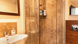 A modern bathroom with a glass-enclosed shower, a white sink, and toiletries on a shelf. - Entire Family Apartment- Edinburgh (Edinburgh)