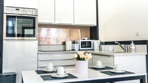 A modern kitchen with stainless steel appliances, a microwave, and a coffee maker. There is a table with a vase of flowers and tea sets. - Entire Family Apartment- Edinburgh (Edinburgh)