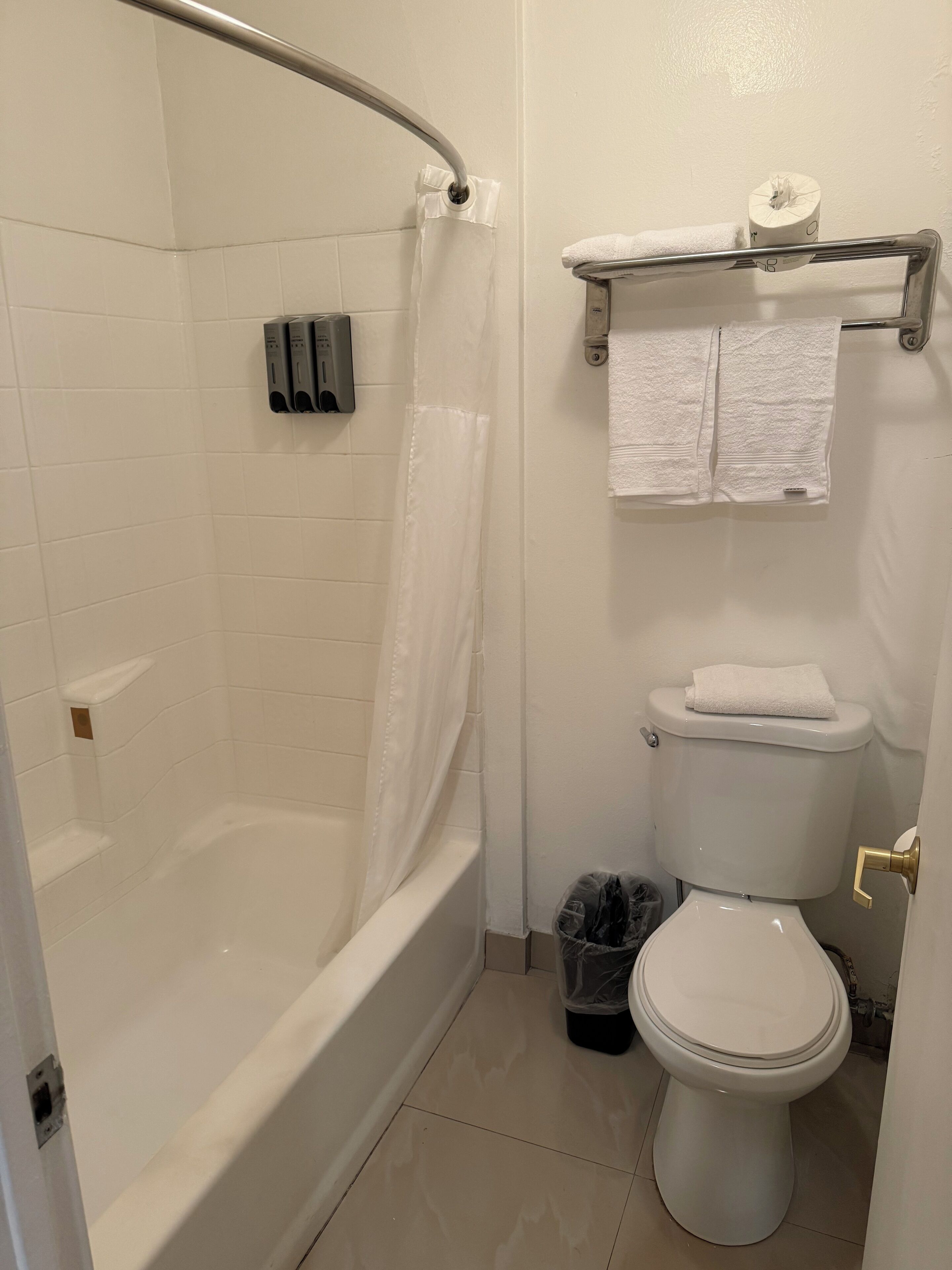 A bathroom with a bathtub, toilet, and a towel rack.