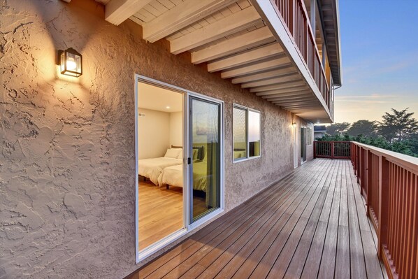 A balcony with wooden flooring and a stone wall.