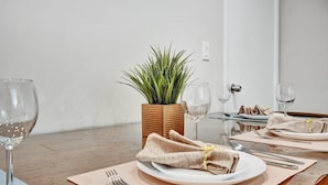 Uma mesa de jantar posta com pratos, talheres e taças de vinho, com um vaso de planta no centro.