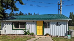A small, single-story building with a green roof and a yellow door.