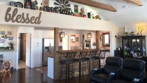 Un amplio salón con cocina y zona de bar. Se ve un letrero grande con la palabra 'blessed'.