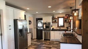 Una cocina con armarios blancos, electrodomésticos de acero inoxidable, piso de tablones y una isla de madera.