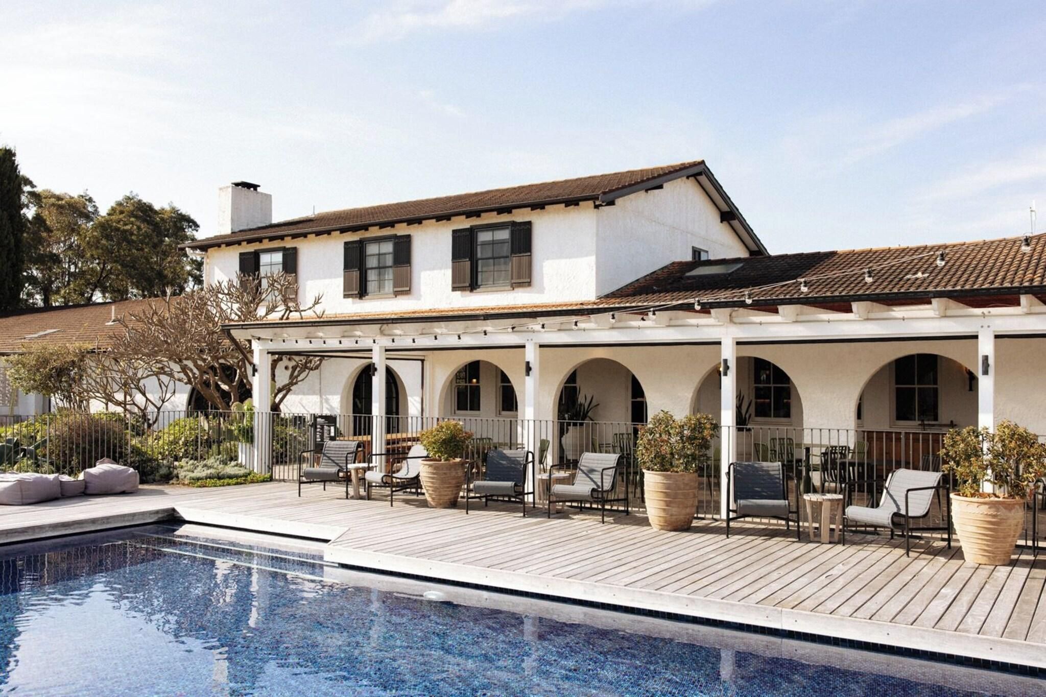 A poolside area with a covered patio, outdoor seating, and a swimming pool.