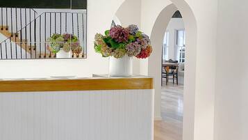 A reception area with a white reception desk, a mirror, and a floral arrangement.