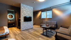 Una sala de estar moderna con un sofá, una mesa de centro y un televisor montado en una pared con estampado floral.
