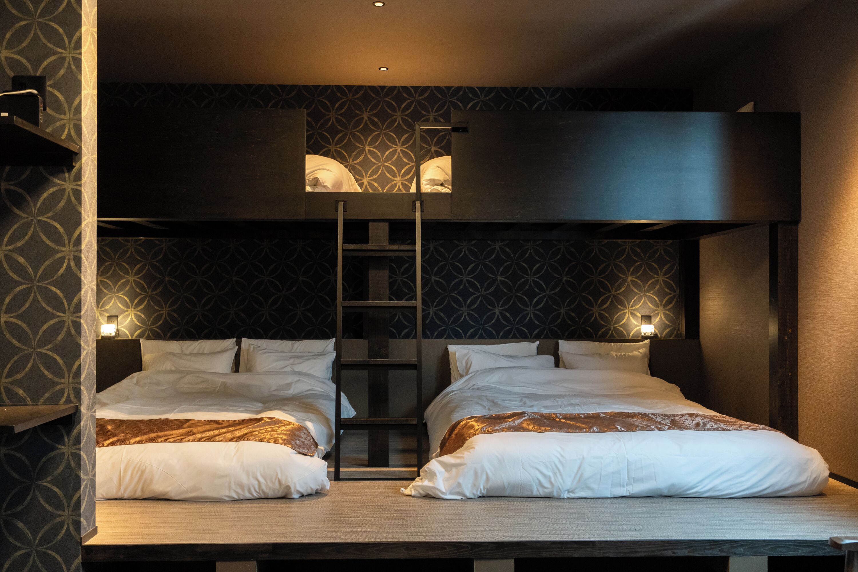 Habitación de hotel con dos camas, una escalera y una lámpara fijada a la pared.