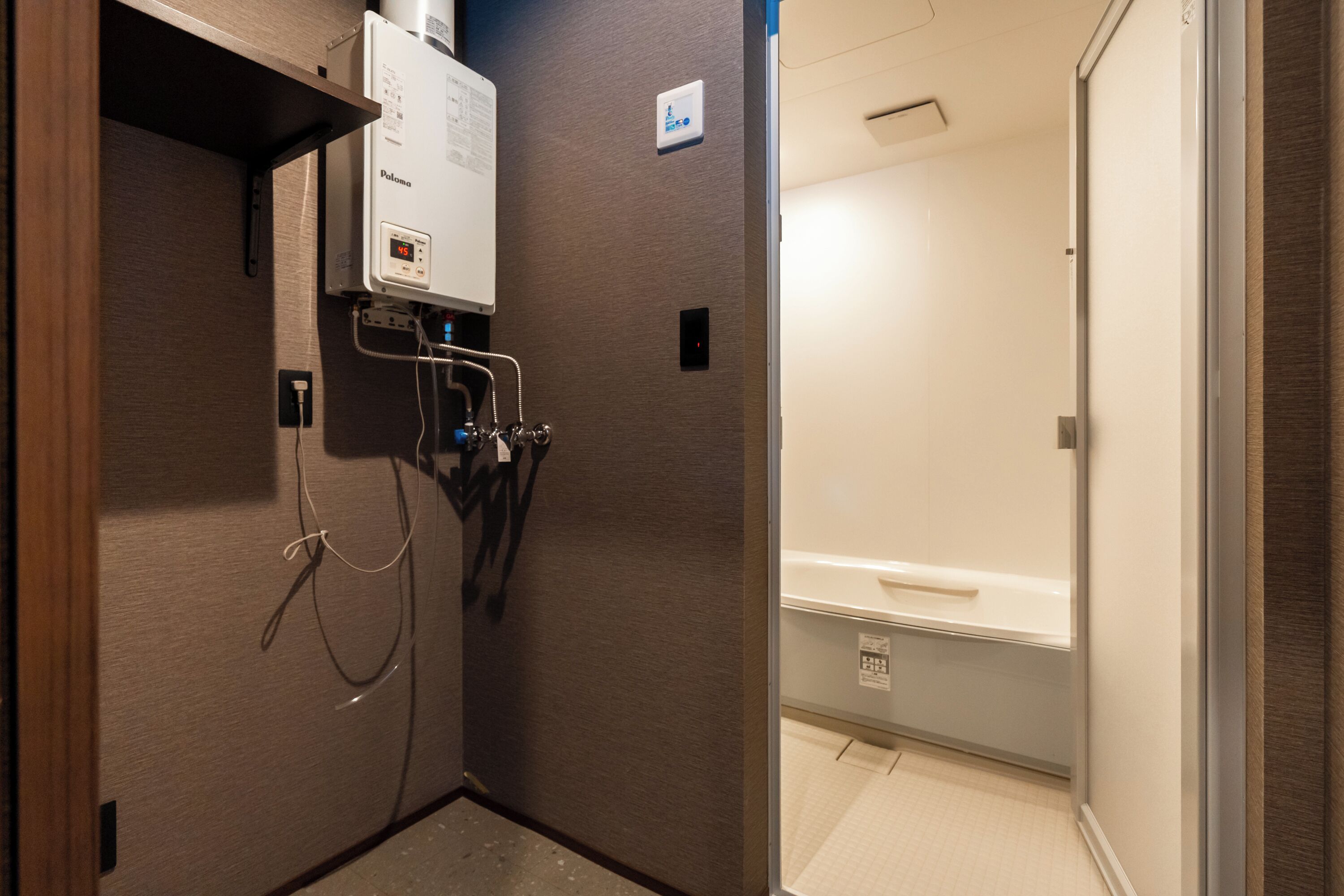 A bathroom with a shower, toilet, and a control panel on the wall.