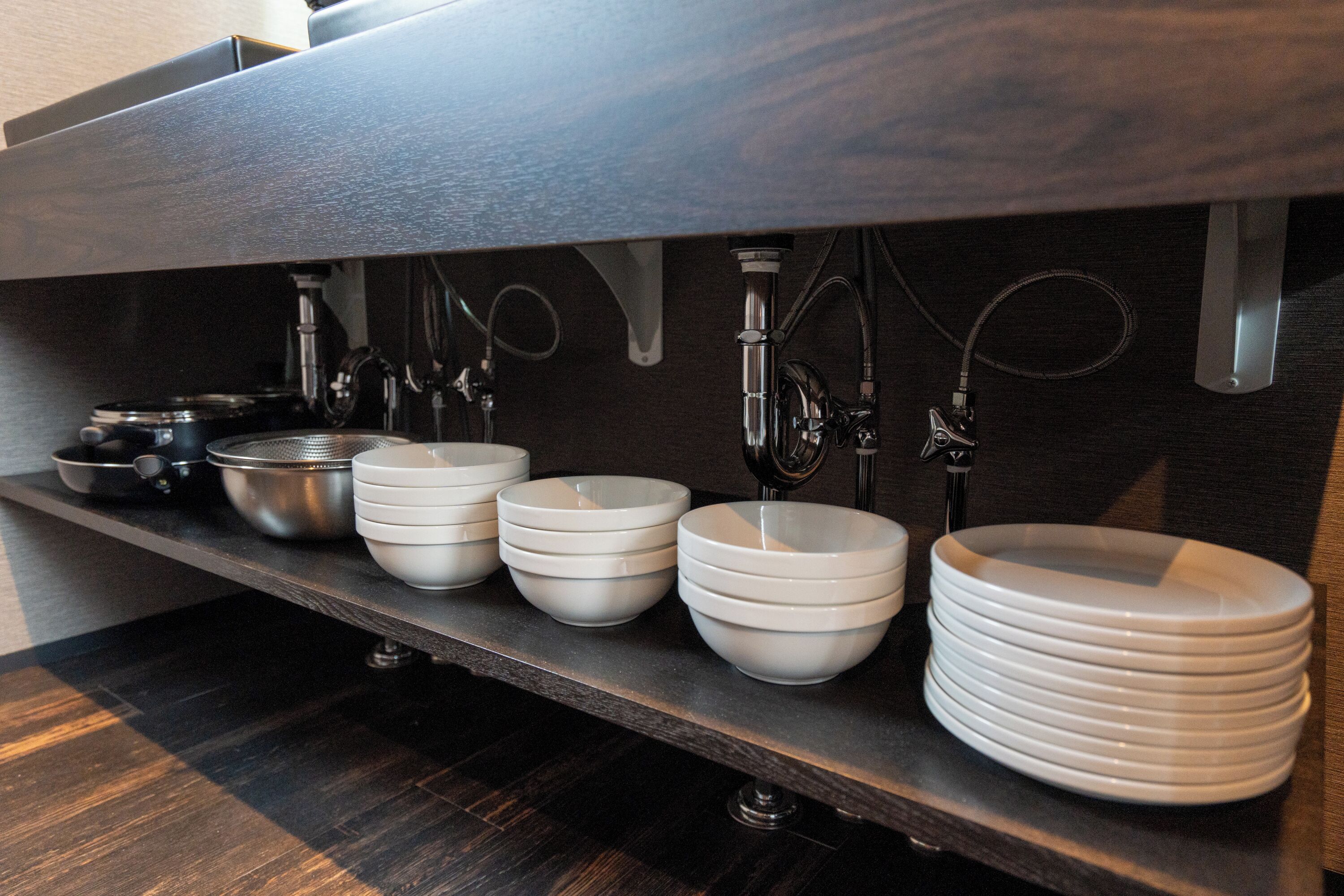 A kitchen counter with various bowls and a stack of plates.