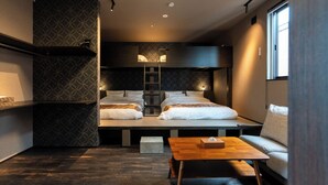 Habitación de hotel pequeña con una litera, una mesita y una escalera.