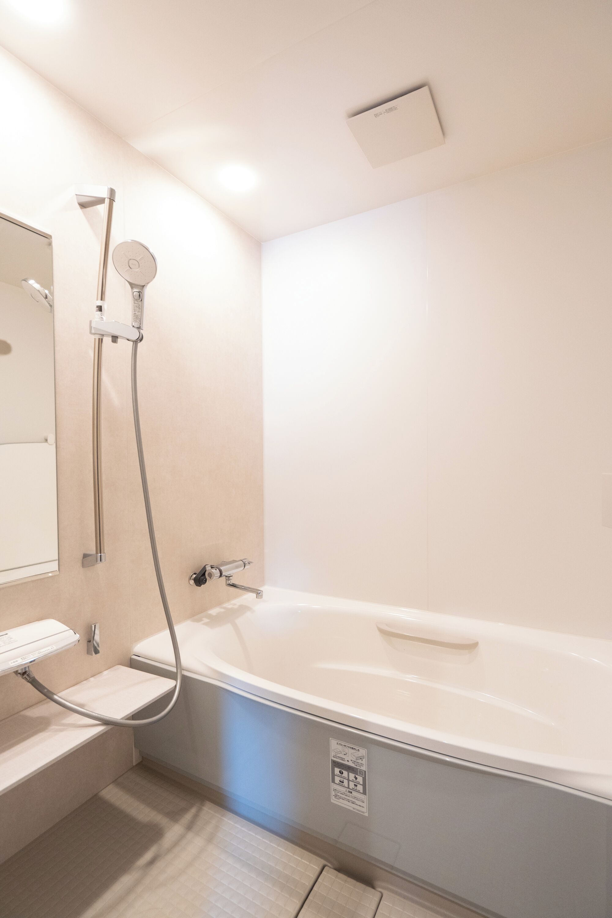 A modern bathroom with a bathtub, a handheld showerhead, a wall-mounted towel rack, and a mirror.