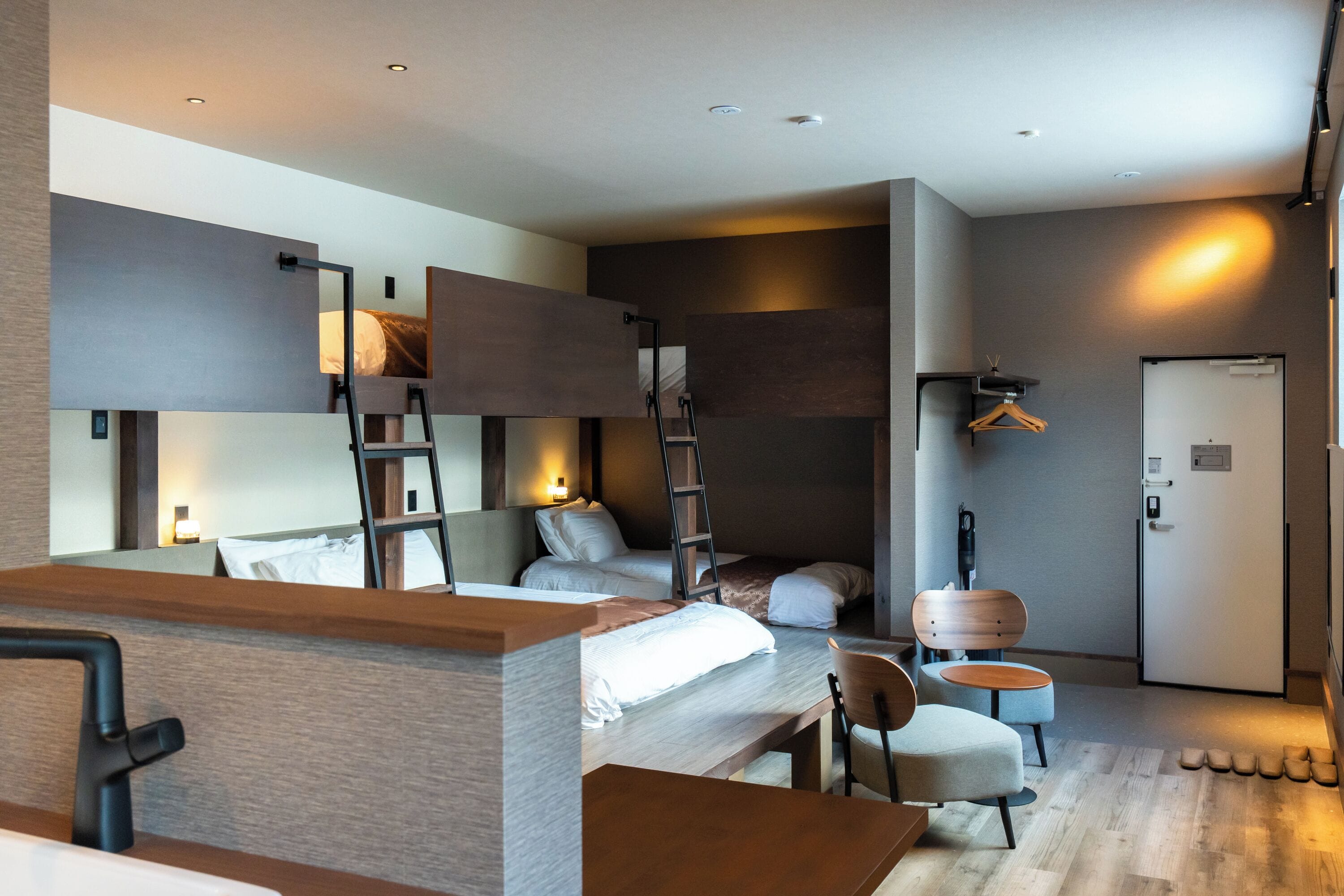 A modern hotel room with a bed, a desk, a chair, a wardrobe, and a wardrobe mirror.