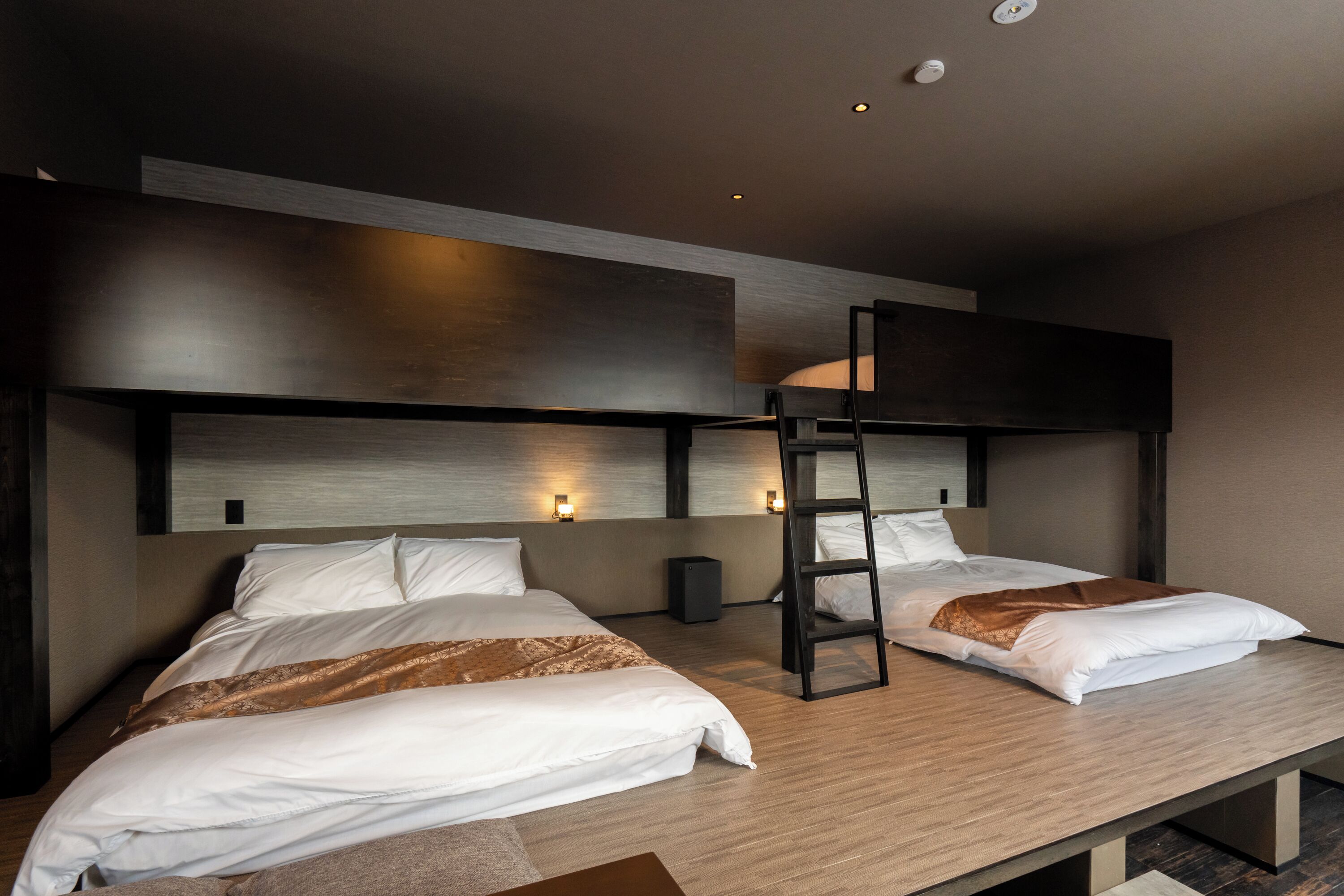 A modern hotel room with two beds, a wooden floor, and a wall-mounted ladder.