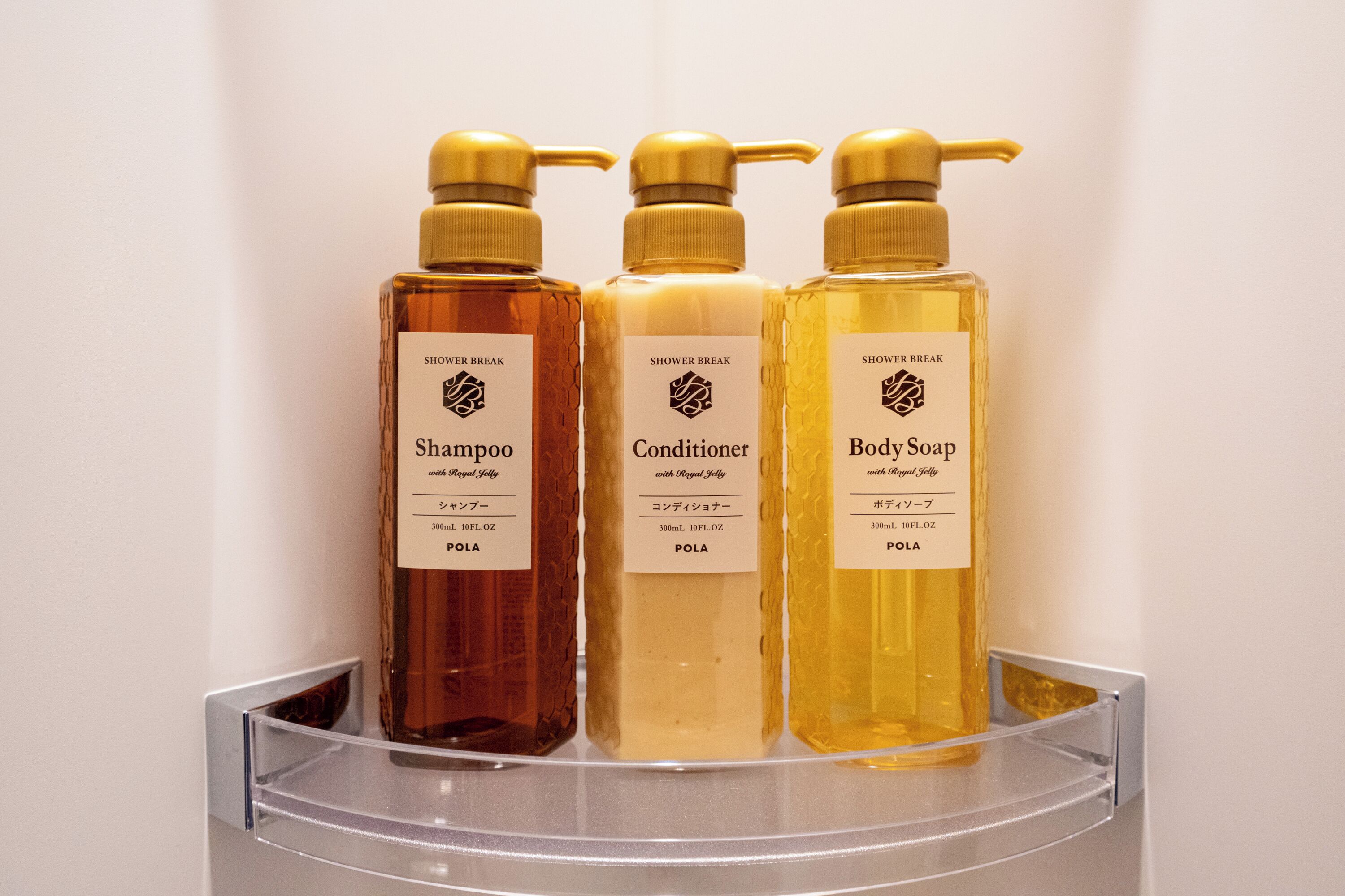 Tres botellas de productos de baño sobre una repisa.