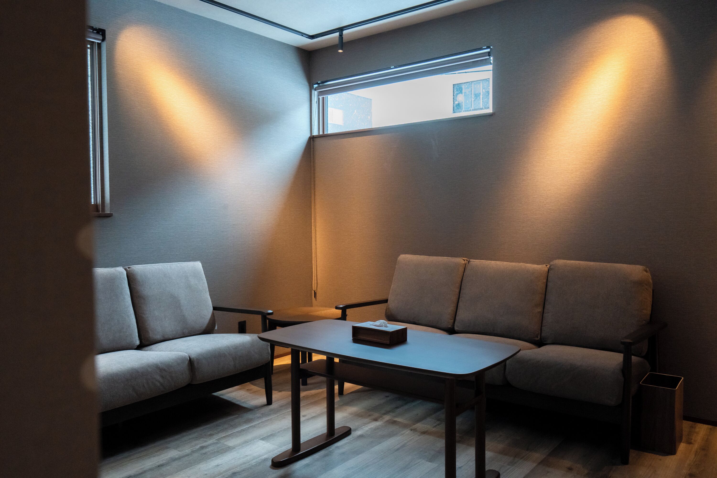 Una sala moderna con un sofá, una mesita de centro y un ventanal pequeño.