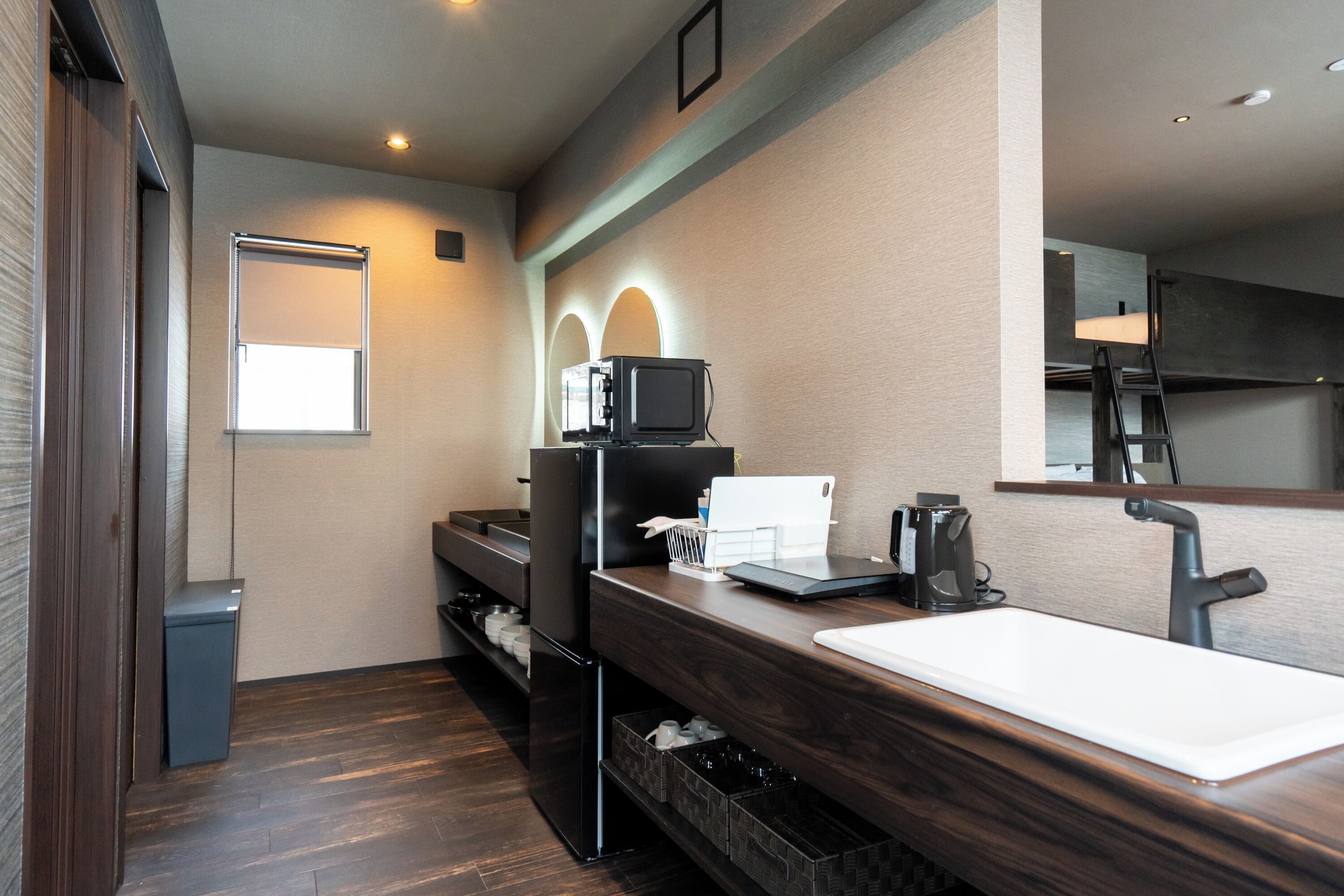 A modern bathroom with a dark wood vanity, a white sink, a mirror, and a built-in microwave.