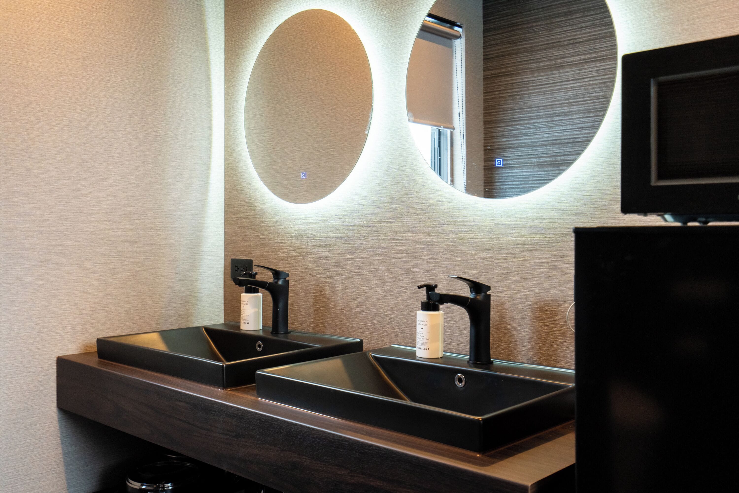 Une salle de bain moderne avec deux lavabos, un miroir et un téléviseur.