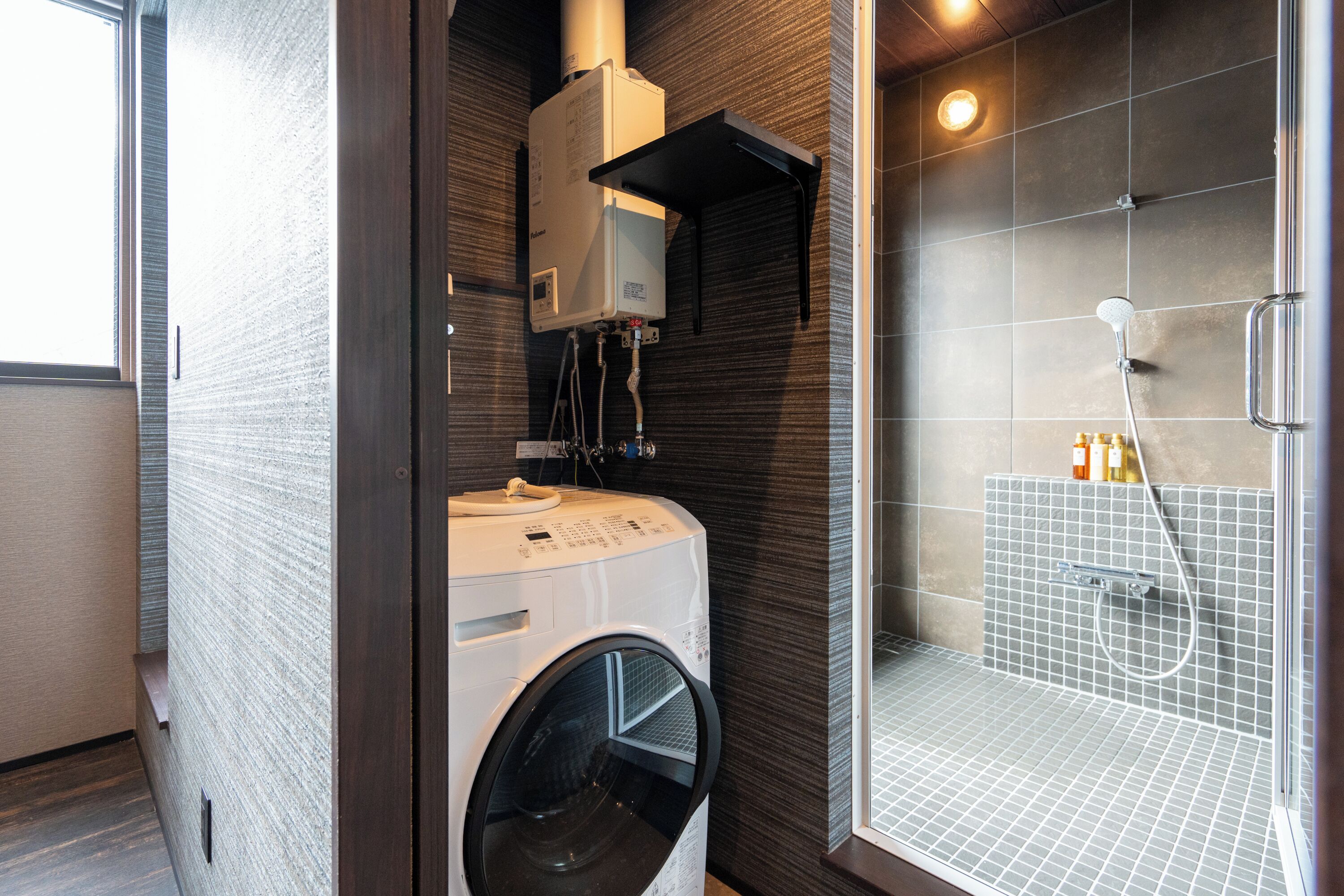 Un baño moderno con lavadora y secadora integradas, cabina de ducha de vidrio y zona de ducha con azulejos.