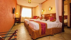 Une chambre d’hôtel avec deux lits, une télévision et une fenêtre avec des rideaux.