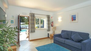 Ein Wohnzimmer mit einem blauen Sofa, einem blauen Teppich, einem Holztisch und einem Fenster mit Vorhängen.